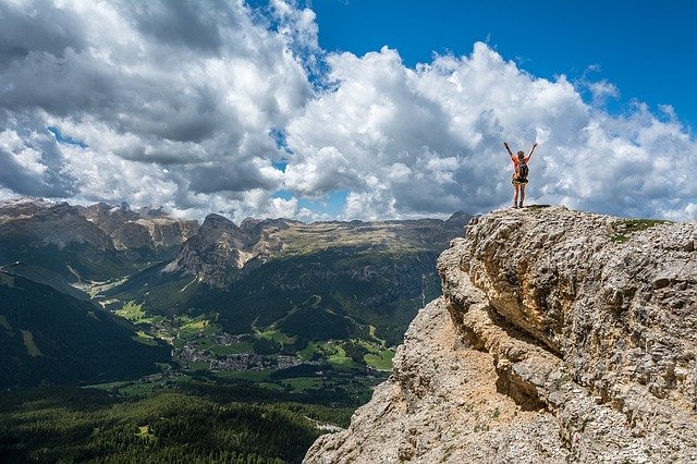 Person on top of mountain with arms stretched in victory pose.